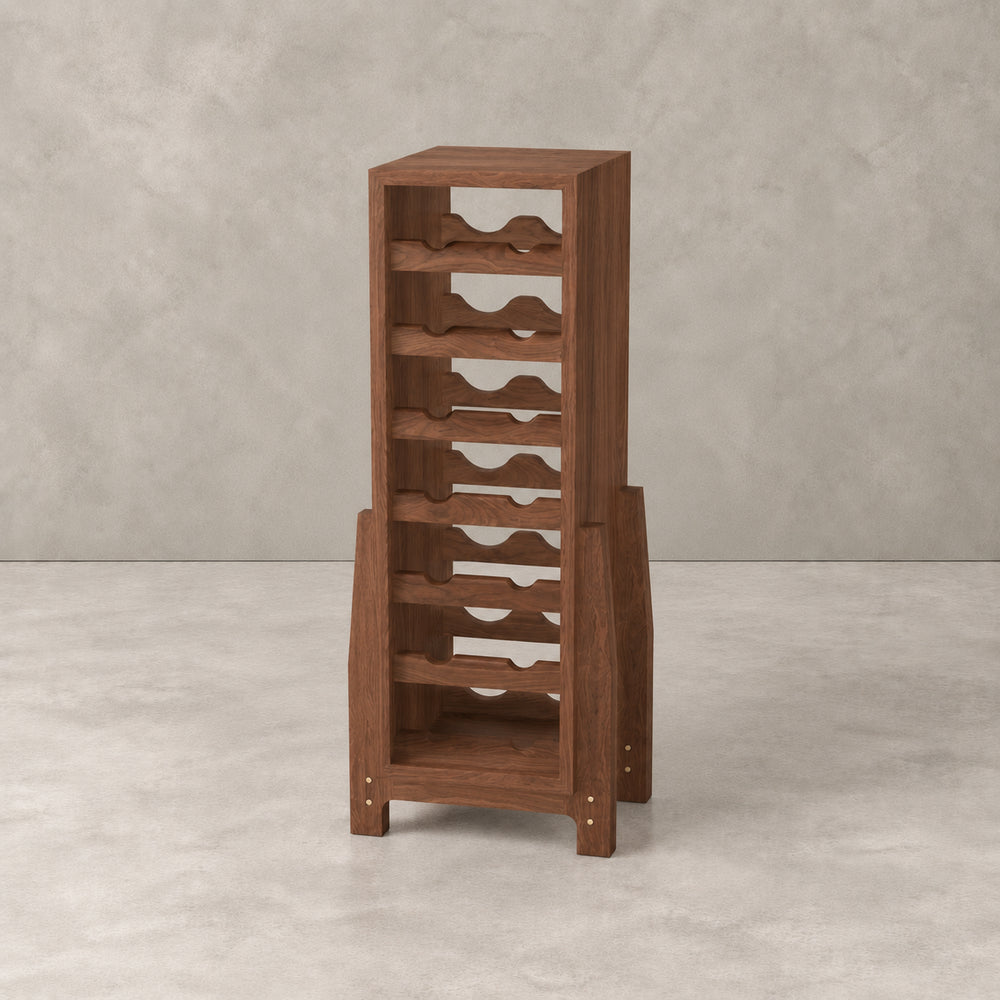 A tall wooden wine rack with multiple staggered bottle-holding shelves and a lower open storage compartment, shown in a warm medium-brown finish against a textured light gray studio backdrop.