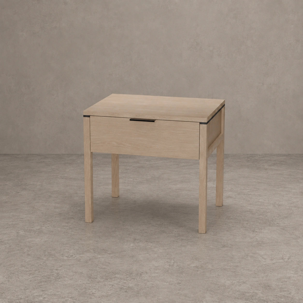 A light natural oak nightstand with a single drawer and a slim black metal handle, set against a textured gray concrete wall and floor.