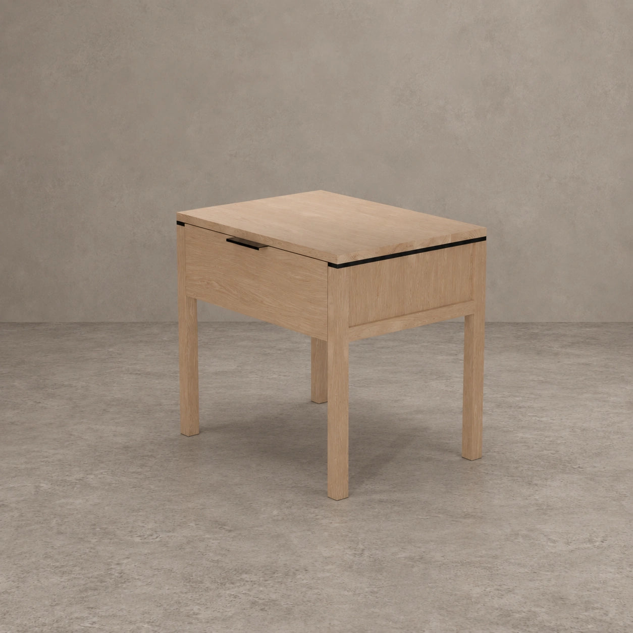 A light oak wood nightstand with a single drawer, featuring a black metal handle and a thin black accent line along the top edge, set against a textured gray concrete wall and floor.